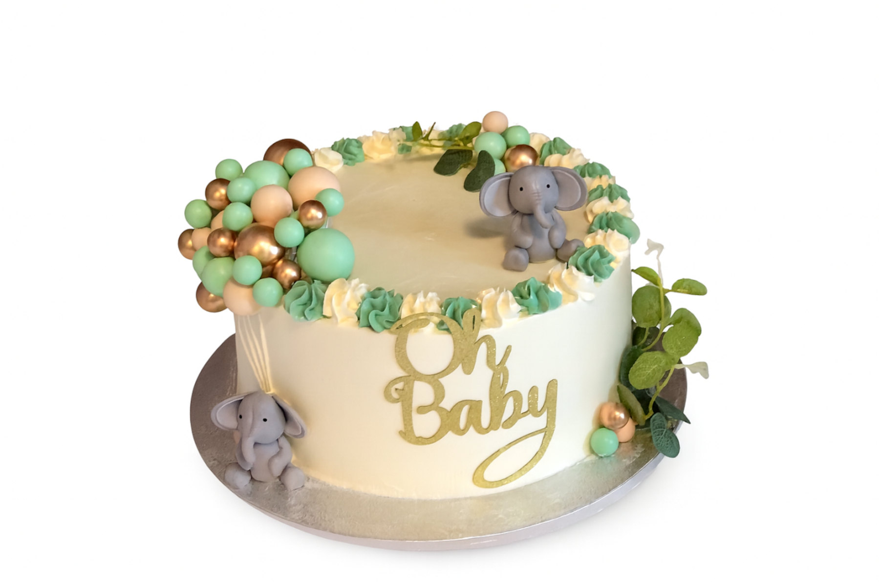 Baby-shower cake in ivory buttercream with a green and cream rosette border, two grey fondant elephants, a cluster of mint, peach and gold balloons and a gold glitter Oh Baby cutout on the side.