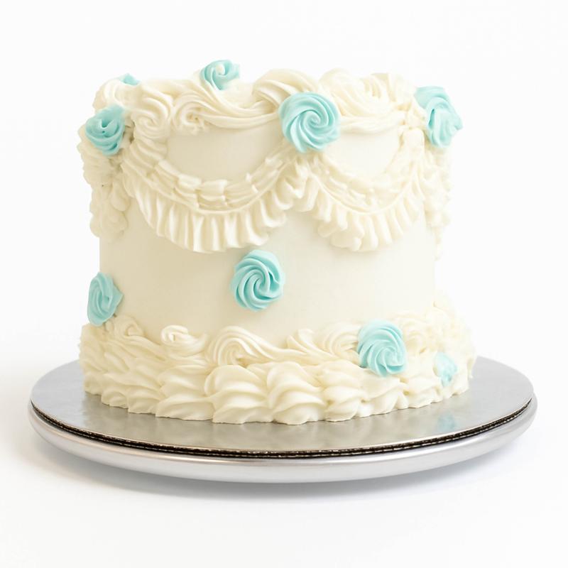 Vintage Lambeth-style cake in ivory buttercream with piped swags, ruffled borders and pale teal rosettes, on a silver board.