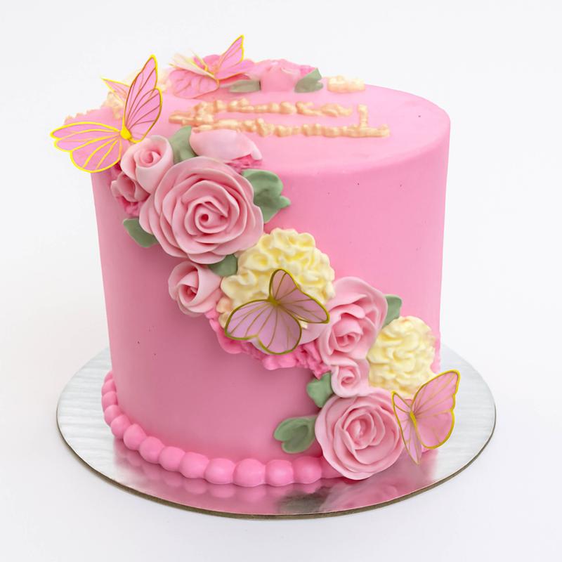 Bright pink cake with a diagonal cascade of fondant roses and cream hydrangeas, gold-edged pink butterflies and a piped pearl border at the base.