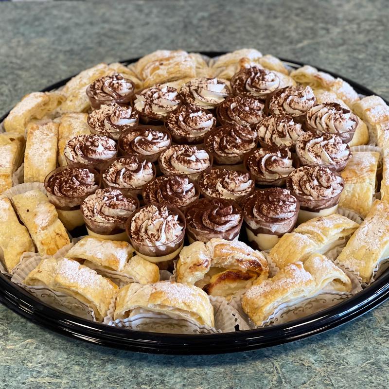 Round platter with a centre of cocoa-dusted tiramisu cups ringed by puff-pastry turnovers dusted with icing sugar.