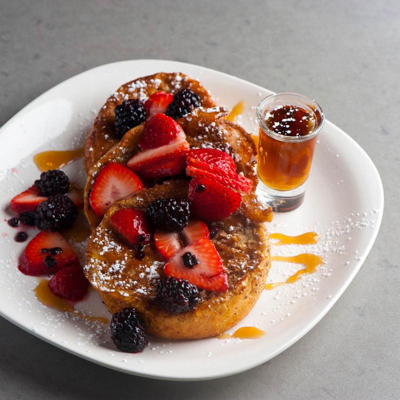 French toast with berries on top and maple syrup.