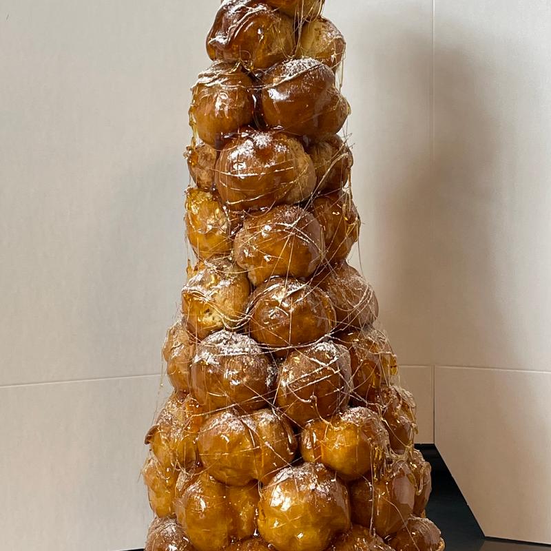 Tall croquembouche of glazed choux puffs dusted with icing sugar and wrapped in fine threads of spun caramel.