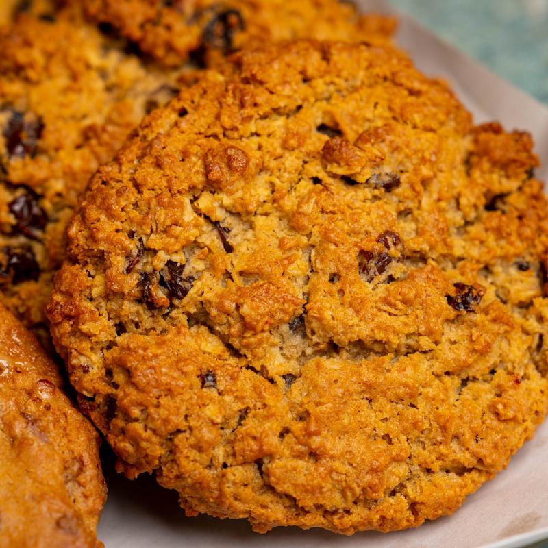 Close-up of thick oatmeal raisin cookies with a craggy golden crust.