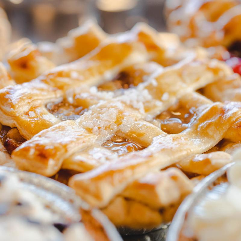 Close-up of individual lattice-topped fruit pies, the pastry glazed and scattered with coarse sugar.