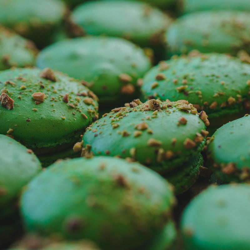 Close-up of green macaron shells scattered with chopped pistachios.