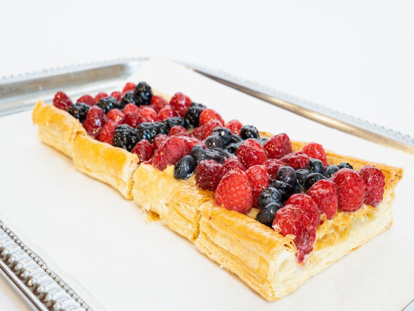 Long fruit tart on puff pastry with fresh berries